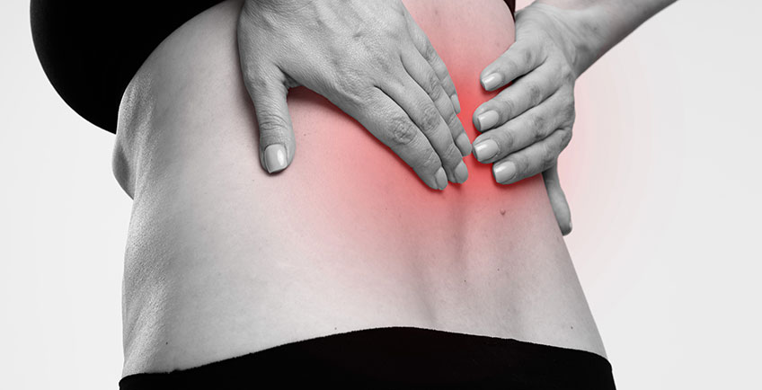 Person holding lower back with localized pain