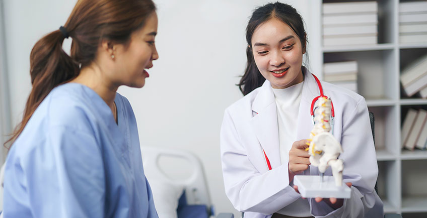 Clinician explaining a spine model during a pain evaluation
